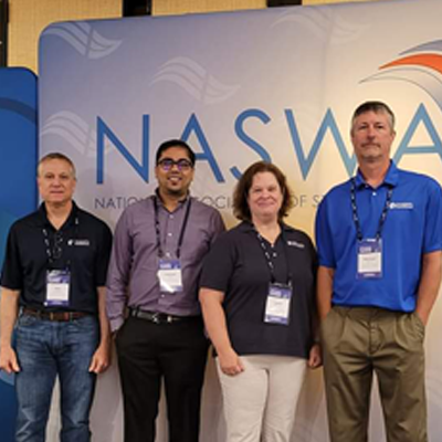 In this picture, a group of employees are posing in front of our GUS and REX software mascots at the 2016 Workforce Technology Conference.